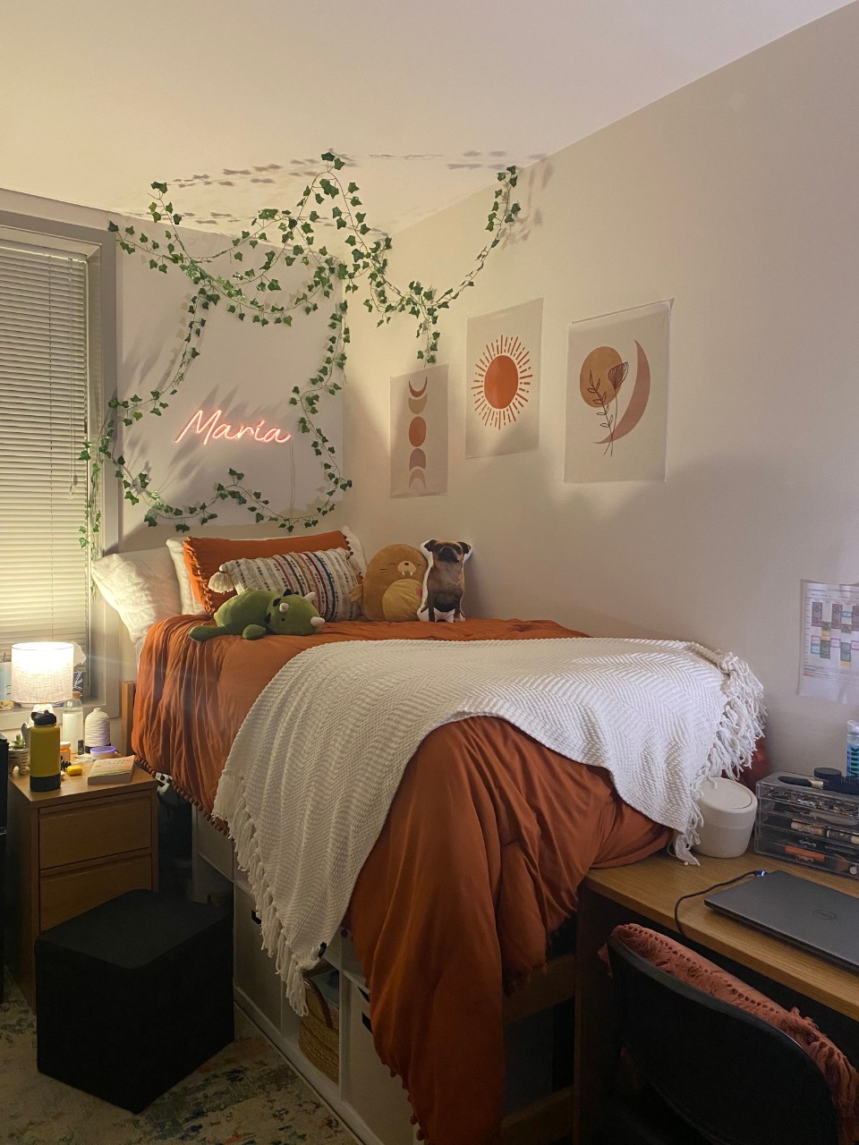 Bed with orange and white linens and a few stuffed animals and vine decal hanging over the bed