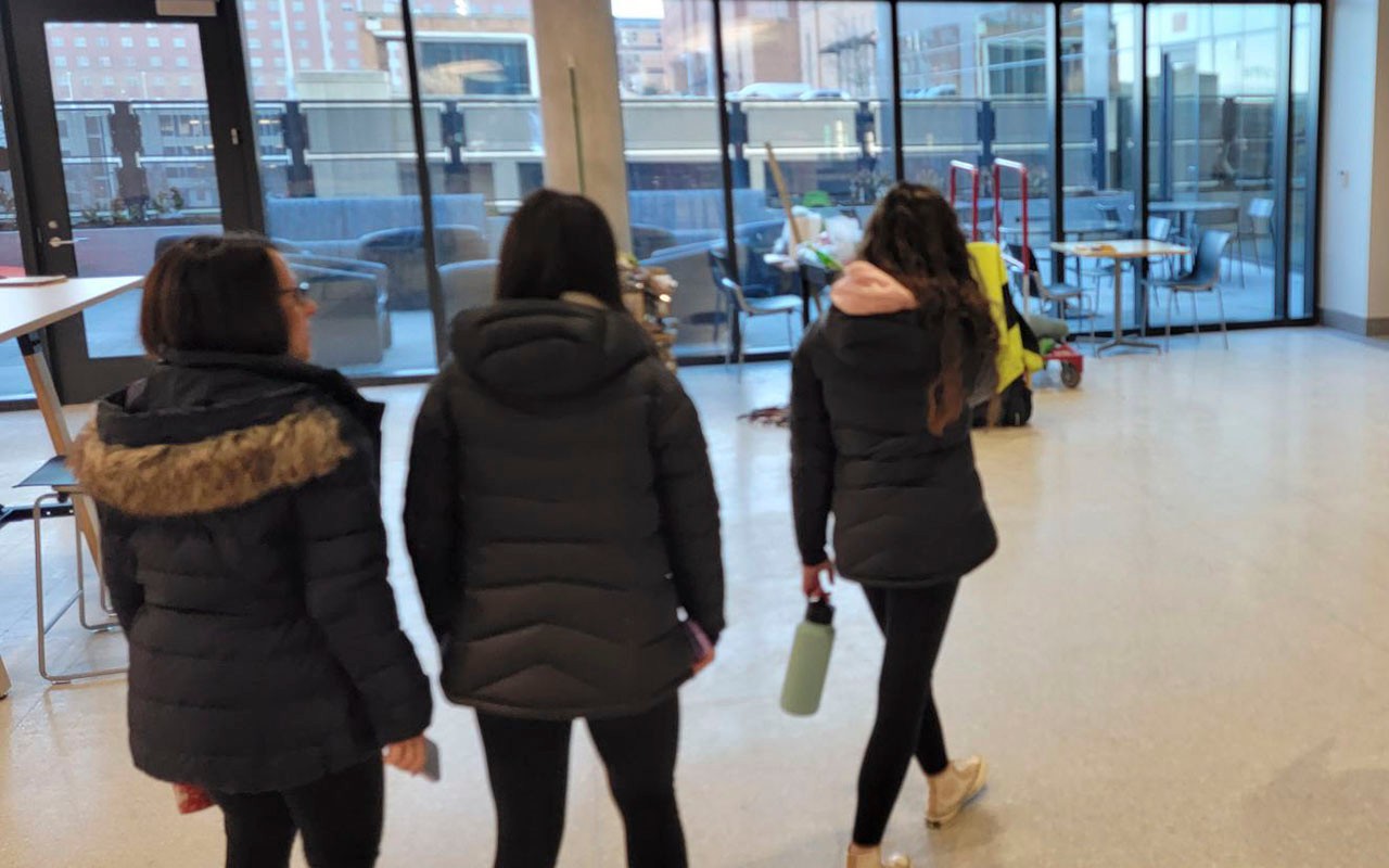 Three students in lobby looking out at patio