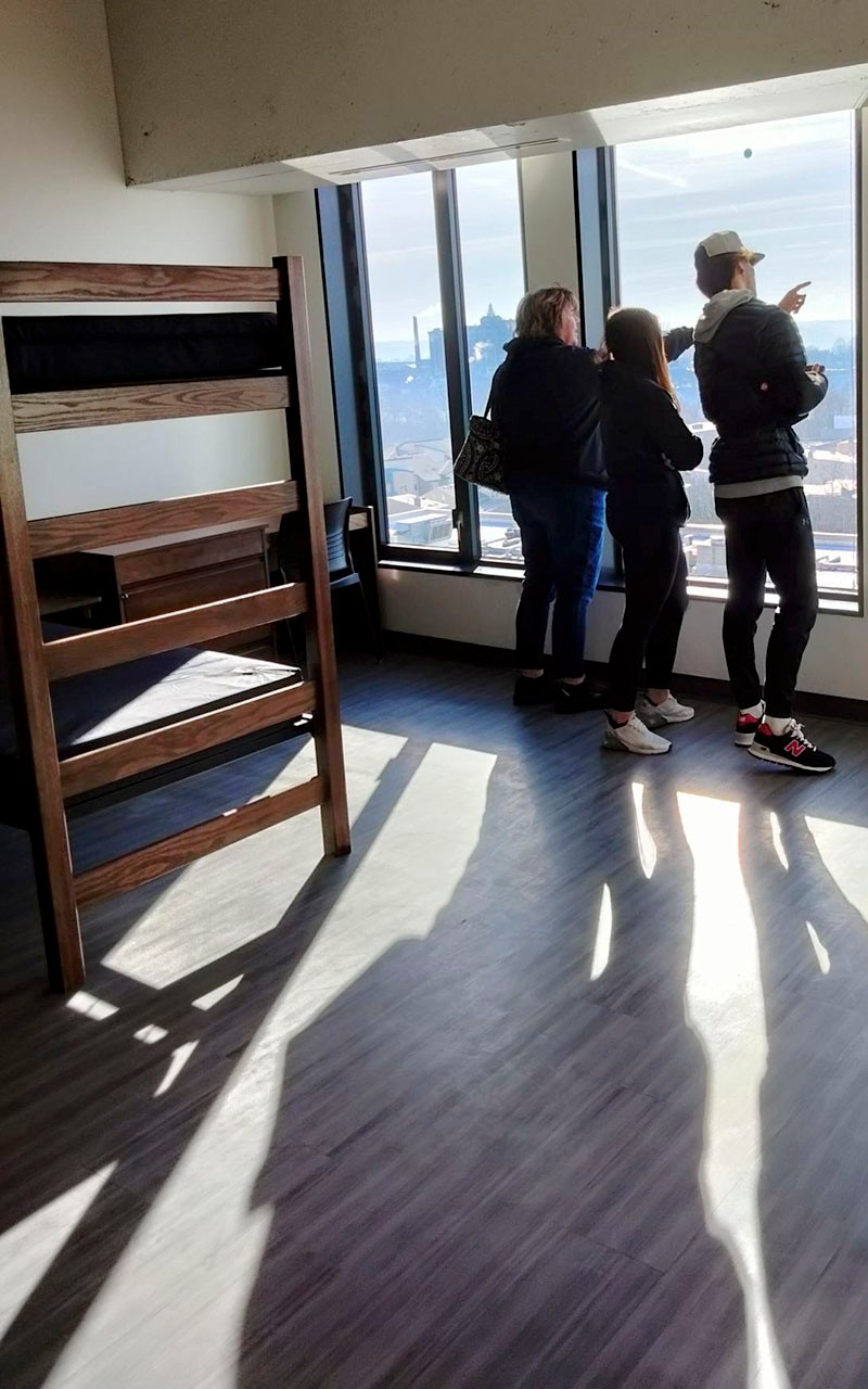 Family looking out of window of room with 2 sets of bunk beds